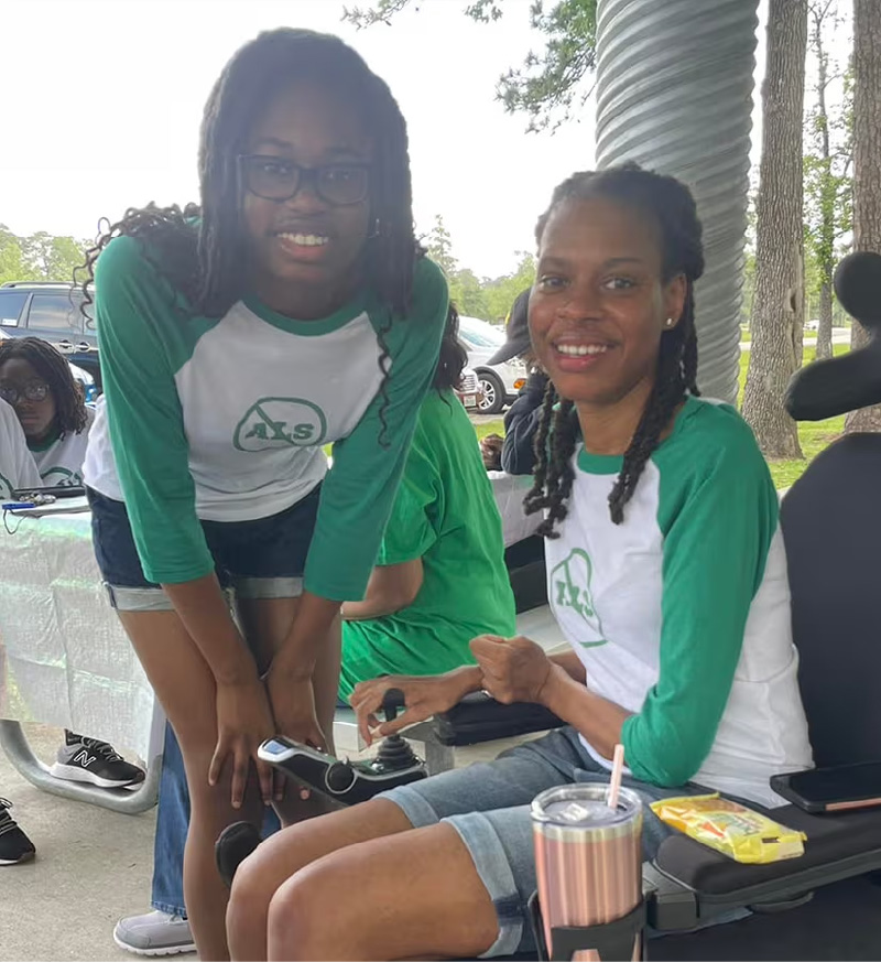 Photo of a mother using a wheelchair posing with her teenage daughter.